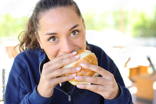 Woman eating a burger looking at camera