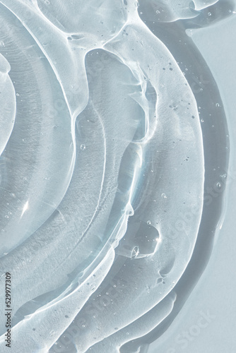 Drops of serum or hyaluronic acid gel on a pink background. Smears of cosmetic skin care products. Wellness and beauty concept.