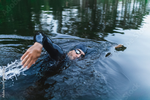 Man wearing wetsuit swimming in lake