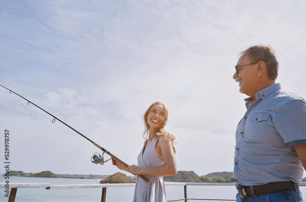 Happy young woman learning fishing from father on weekend Happy young woman learning fishing from father on weekend