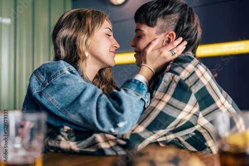 Loving young lesbian couple sitting at table in restaurant photo