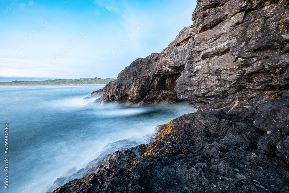 Waves crashing on rock formations by Fairy Bridge in sea