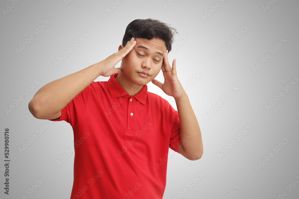 Portrait of sick Asian man having a migraine, touching his temple. Isolated image on gray background. Headache disease concept Portrait of sick Asian man having a migraine, touching his temple. Isolated image on gray background. Headache disease concept