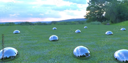 Photography Shiny metal balls stick out of the ground on a field covered with green grass, reflecting the cloudy evening sky