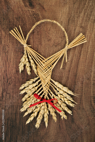 Corn husk doll for farm house protection blessing. Pagan symbol of fertility, success, good fortune, natural straw object also used in harvest rituals. On rustic wood.