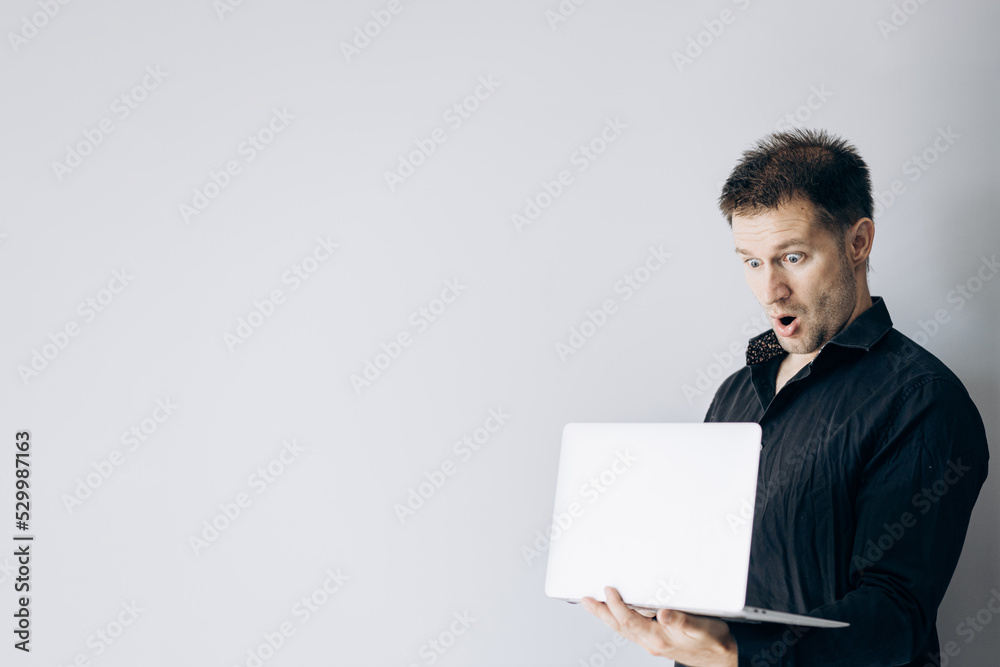 IT man in a black shirt stands confidently and holds a laptop. IT man in a black shirt stands confidently and holds a laptop.