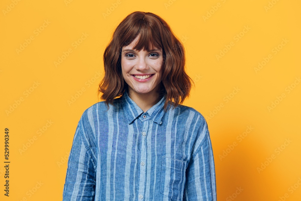 horizontal photo on a yellow background of a cute, happy woman in a blue shirt horizontal photo on a yellow background of a cute, happy woman in a blue shirt