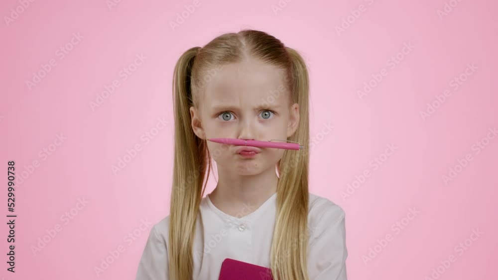Mustache joke. Close up portrait of positive little schoolgirl holding pencil between nose and lips, fooling around Mustache joke. Close up portrait of positive little schoolgirl holding pencil between nose and lips, fooling around