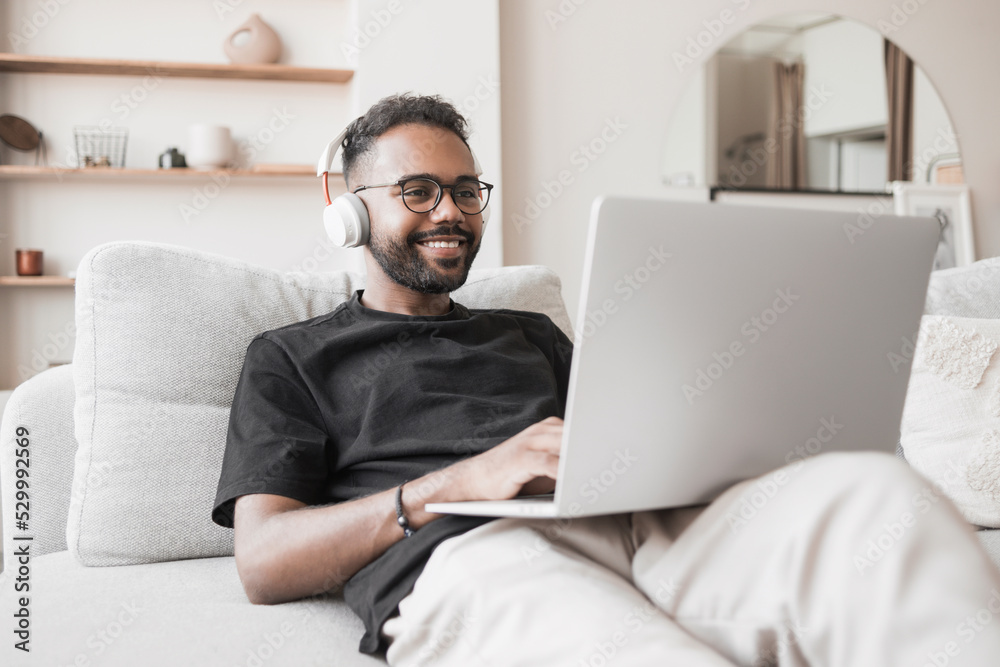 Handsome young man using laptop computer at home. Student men resting in his room. Home work or study, freelance and communication concept