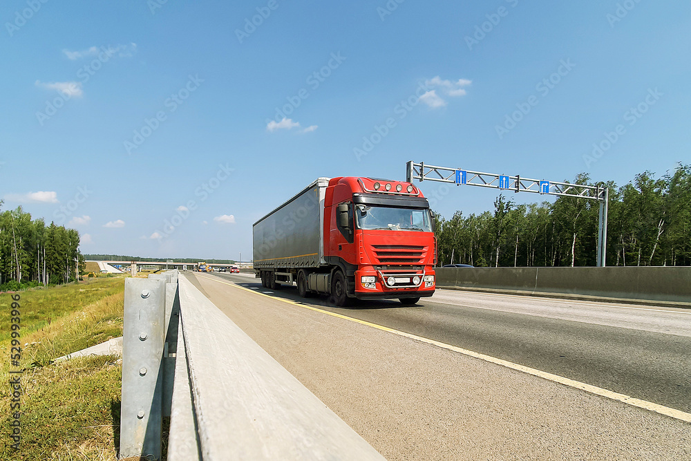 A red truck is moving along the autobahn. Freight, container transportation.