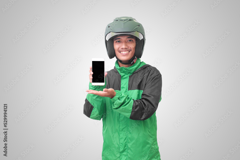 Portrait of Asian online taxi driver wearing green jacket and helmet showing and presenting blank screen mobile phone. Advertising concept. Isolated image on white background Portrait of Asian online taxi driver wearing green jacket and helmet showing and presenting blank screen mobile phone. Advertising concept. Isolated image on white background