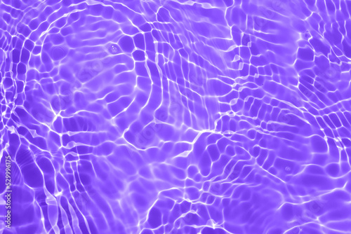 Defocus blurred transparent purple colored clear calm water surface texture with splash, bubble. Shining purple water ripple background. Surface of water in swimming pool. Tropical purple water color.