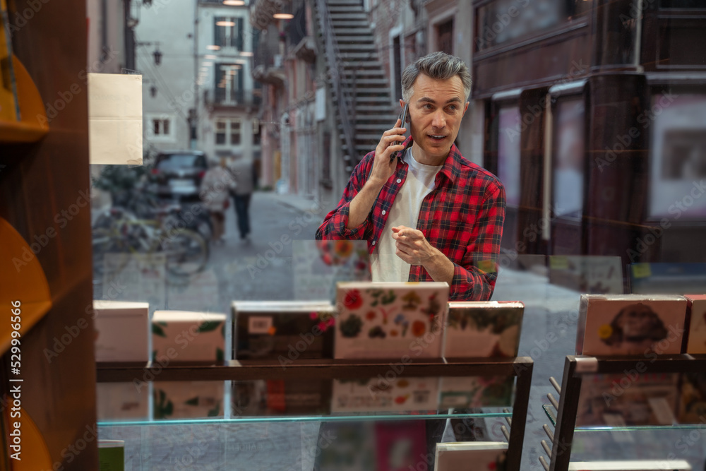 Man in plaid shirt with a phone near the show window