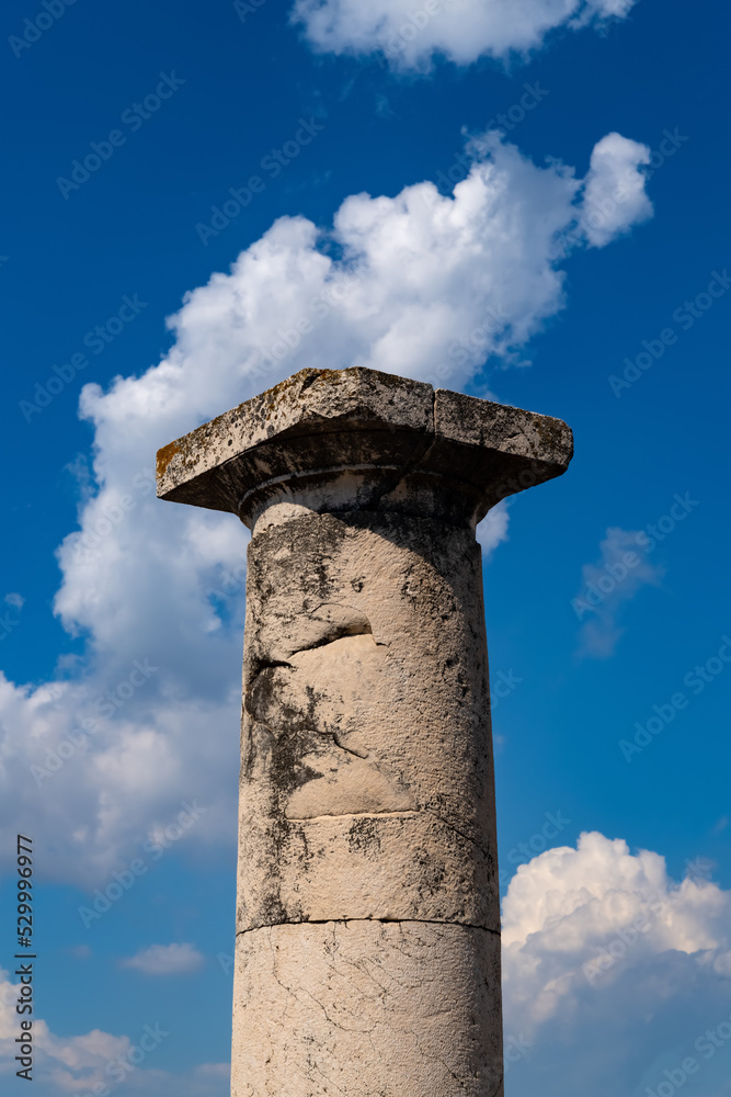 Historic column in famous excavated comune of Pompei near Naples Italy on sunny summer day with blue cloudy sky. The roman city was buried under the ashes of Vesuvius volcano and now is popular sight.