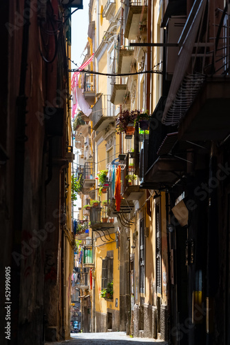 Fototapeta Naklejka Na Ścianę i Meble -  Narrow street in old town “Centro storico“ of historic italian metropole Naples. Typical residential buildings in shabby and weathered condition with balconys, drying laundry and colorful facades.