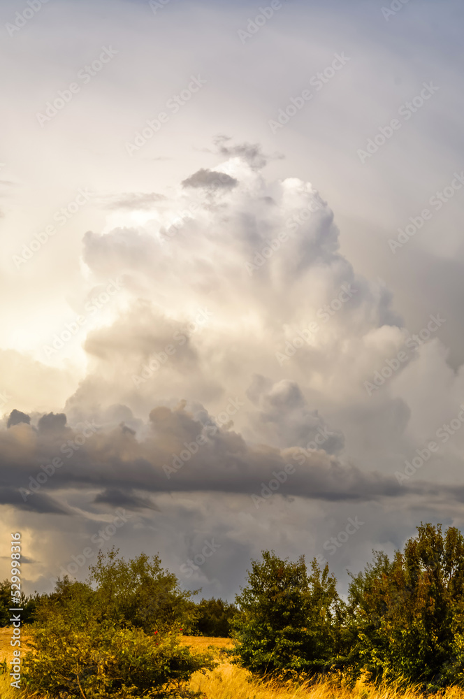 Obraz premium layered storm clouds, heavy rain clouds, landscape before sunset, spectacularly lit by sunlight