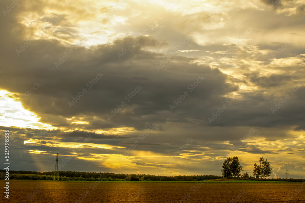 layered storm clouds, heavy rain clouds, landscape before sunset, spectacularly lit by sunlight