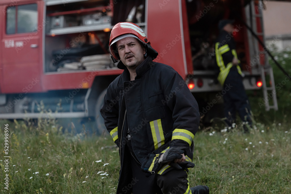 Fototapeta premium depressed and tired firefighter near fire truck. 