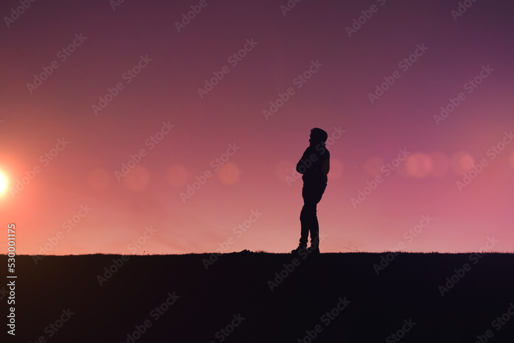 man trekking in the countryside with a beautiful sunset background