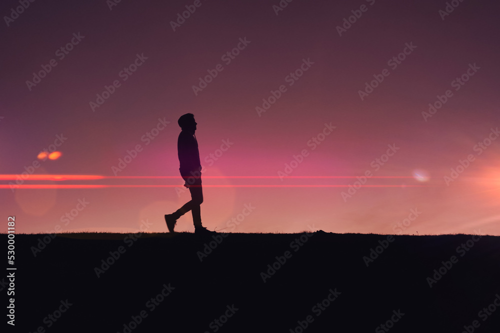 man trekking in the countryside with a beautiful sunset background