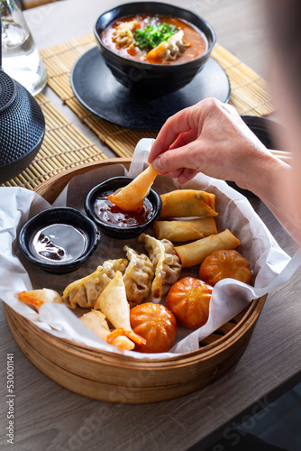woman is eating prawns in batter in a bamboo basket. Traditional Japanese food eaten in a restaurant. © Robert Przybysz