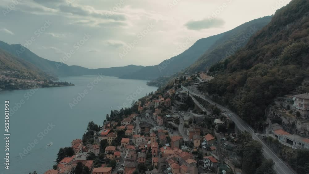 Beautiful aerial of flying slowly along lake como shore at Torriggia showing houses roads, alp mountains - moody cinematic