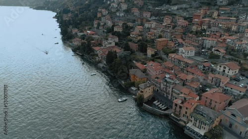 Aerial tilt over lake como village side showing mediterranean houses architecture with alp mountains in the background - moody cinematic photo