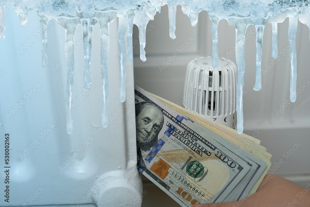 close-up of american dollars banknotes near radiator, temperature regulation in house with thermostat , beginning of heating season close-up of american dollars banknotes near radiator, temperature regulation in house with thermostat , beginning of heating season