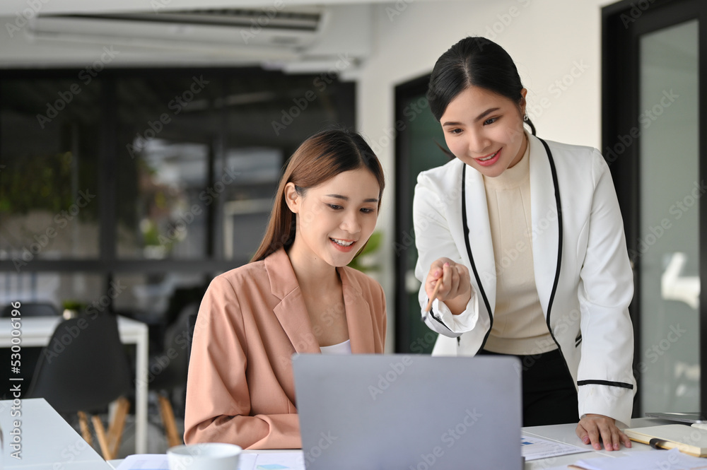 Asian female manager or female boss helping, coaching and training her new assistant Asian female manager or female boss helping, coaching and training her new assistant