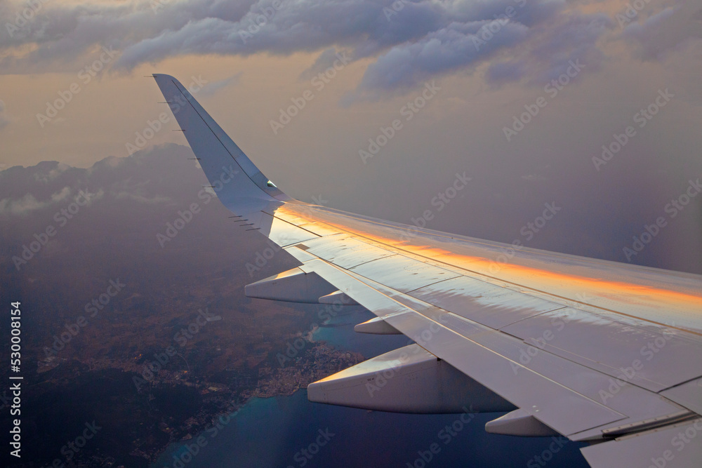 Fototapeta premium sunset seen from aircraft with reflection of sun in wing