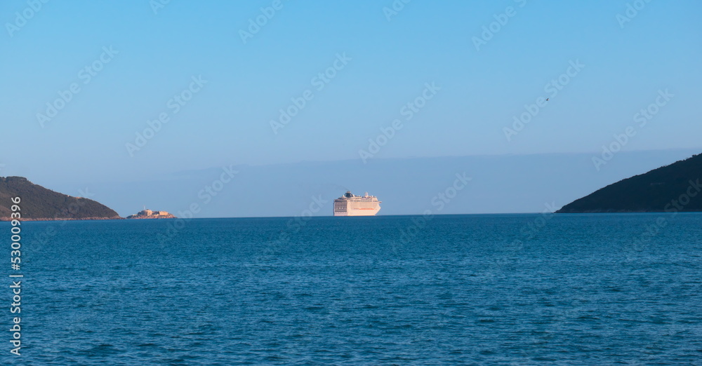 Cruise ship on the horizon leaves the bay into the open sea