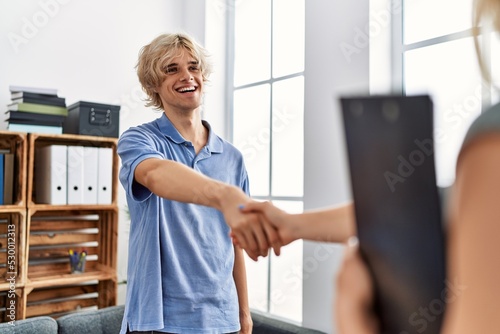 Young blond man patient smiling confident shake hand with therapist at psychology clinic