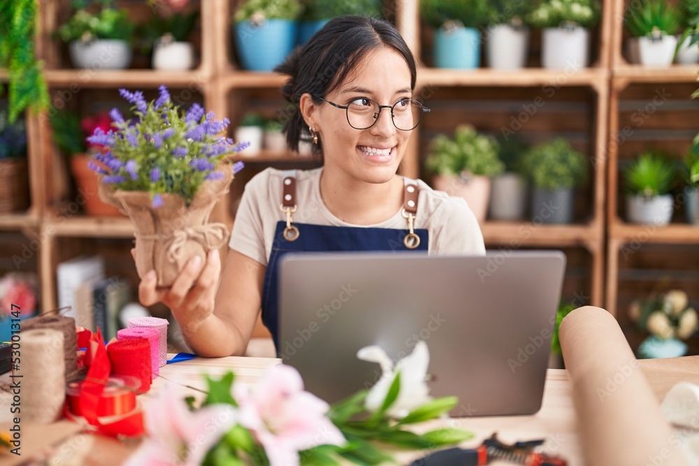 Young hispanic woman working at florist shop doing video call looking away to side with smile on face, natural expression. laughing confident. Young hispanic woman working at florist shop doing video call looking away to side with smile on face, natural expression. laughing confident.