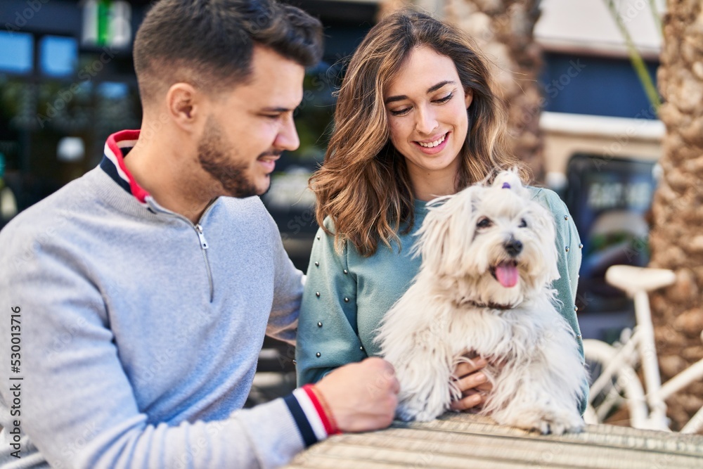 Man and woman holding dog hugging each other at coffee shop terrace Man and woman holding dog hugging each other at coffee shop terrace