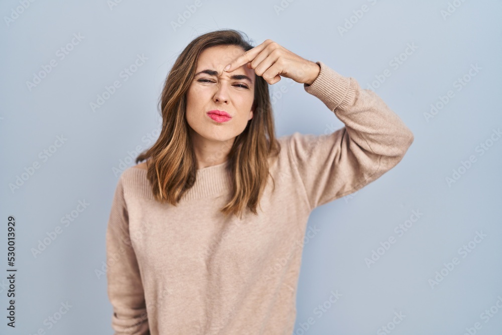 Young woman standing over isolated background pointing unhappy to pimple on forehead, ugly infection of blackhead. acne and skin problem Young woman standing over isolated background pointing unhappy to pimple on forehead, ugly infection of blackhead. acne and skin problem