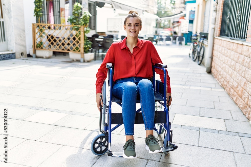Obraz premium Young woman smiling confident sitting on wheelchair at street