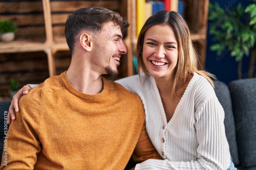 Young man and woman couple hugging each other sitting on sofa at home Young man and woman couple hugging each other sitting on sofa at home