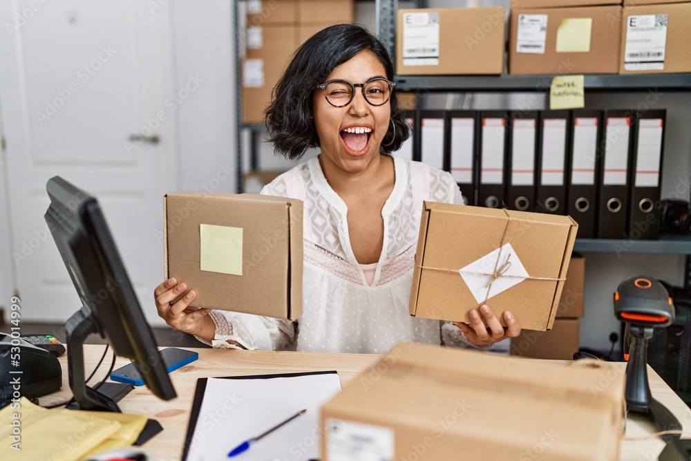 Young hispanic woman working at small business ecommerce winking looking at the camera with sexy expression, cheerful and happy face. Young hispanic woman working at small business ecommerce winking looking at the camera with sexy expression, cheerful and happy face.