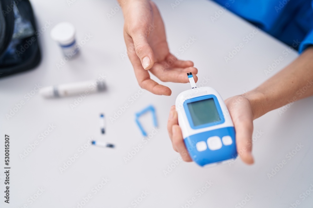 Young woman measuring glucose using glucometer at home Young woman measuring glucose using glucometer at home