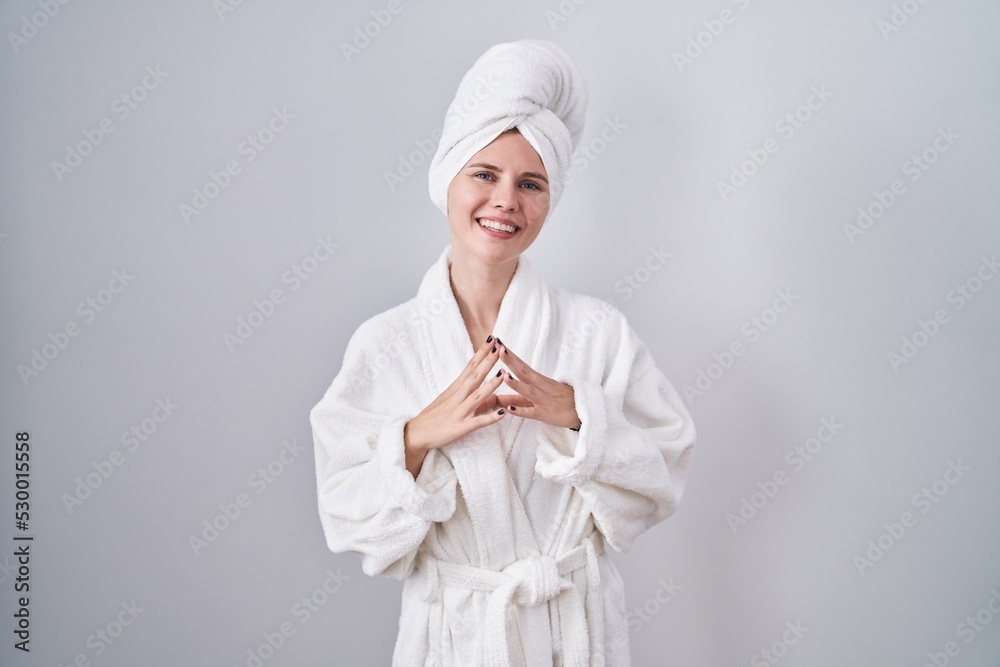 Blonde caucasian woman wearing bathrobe hands together and fingers crossed smiling relaxed and cheerful. success and optimistic Blonde caucasian woman wearing bathrobe hands together and fingers crossed smiling relaxed and cheerful. success and optimistic