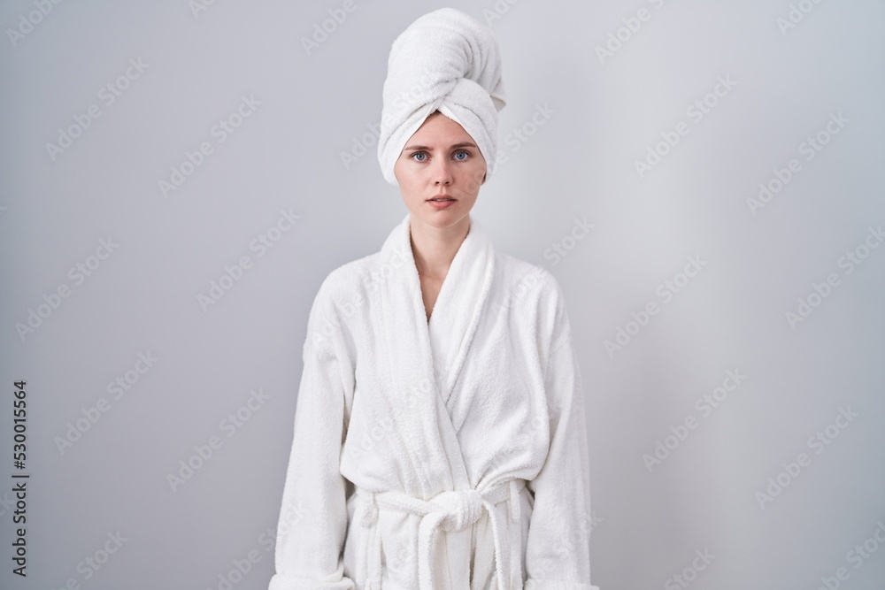 Blonde caucasian woman wearing bathrobe relaxed with serious expression on face. simple and natural looking at the camera. Blonde caucasian woman wearing bathrobe relaxed with serious expression on face. simple and natural looking at the camera.
