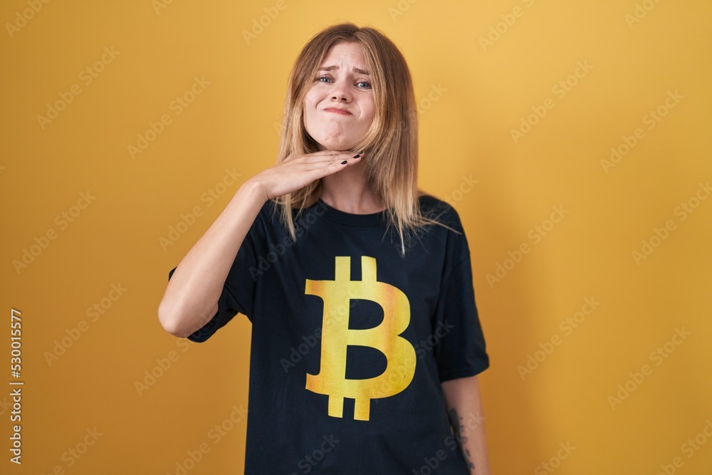 Blonde caucasian woman wearing bitcoin t shirt cutting throat with hand as knife, threaten aggression with furious violence Blonde caucasian woman wearing bitcoin t shirt cutting throat with hand as knife, threaten aggression with furious violence