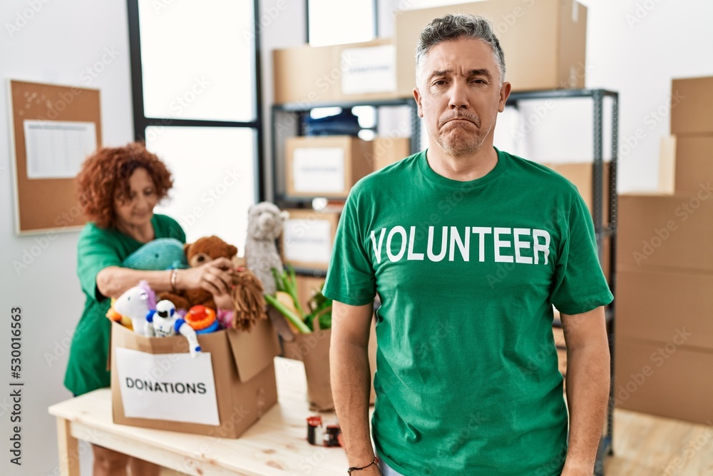Middle age man wearing volunteer t shirt at donations stand depressed and worry for distress, crying angry and afraid. sad expression. Middle age man wearing volunteer t shirt at donations stand depressed and worry for distress, crying angry and afraid. sad expression.