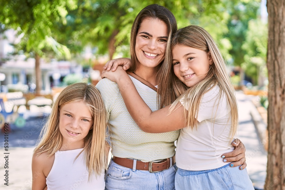 Mother and daughters smiling confident hugging each other standing at park Mother and daughters smiling confident hugging each other standing at park