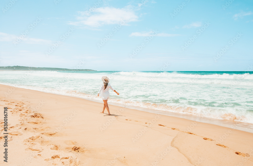 Woman walking along the beach on beautiful summer day in Australia