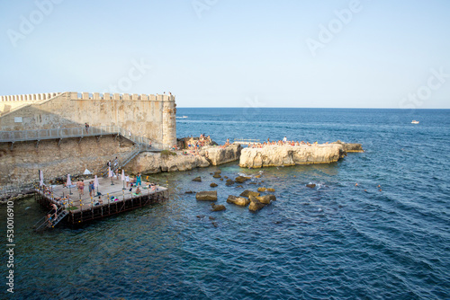 The inhabitants of the city of Syracuse, Italy, sunbathe on the rocks and platforms.