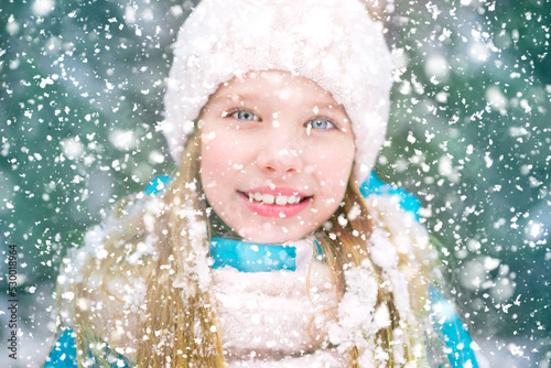 A closeup of blond blue eyed girl in snowflakes.