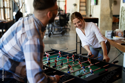 Colleagues having fun at work. Businessman and businesswoman playing table soccer