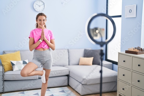 Young beautiful hispanic woman smiling confident having online yoga class at home