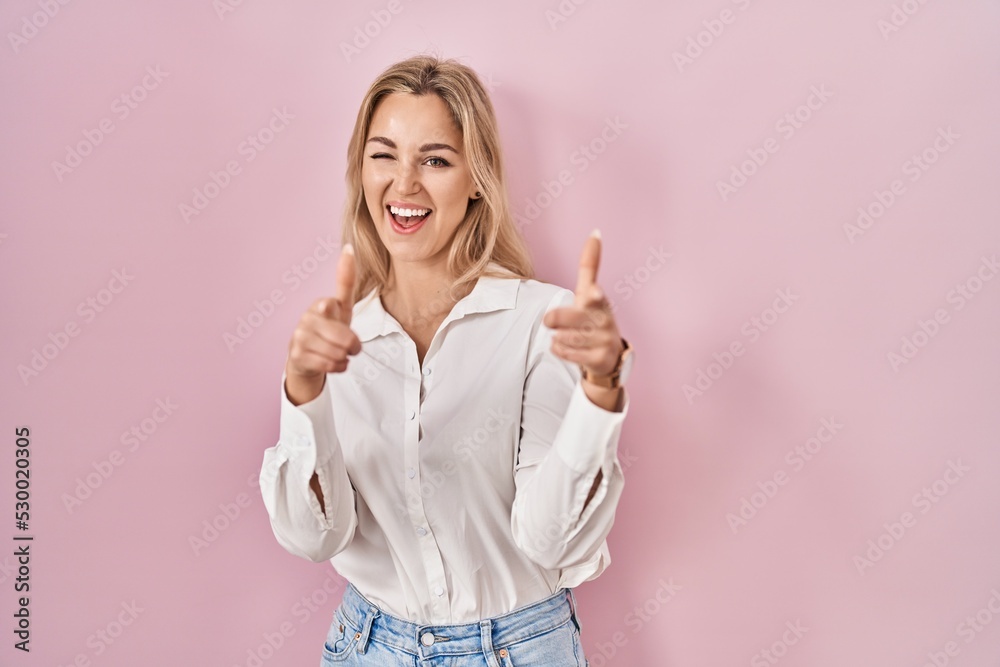 Young caucasian woman wearing casual white shirt over pink background pointing fingers to camera with happy and funny face. good energy and vibes.